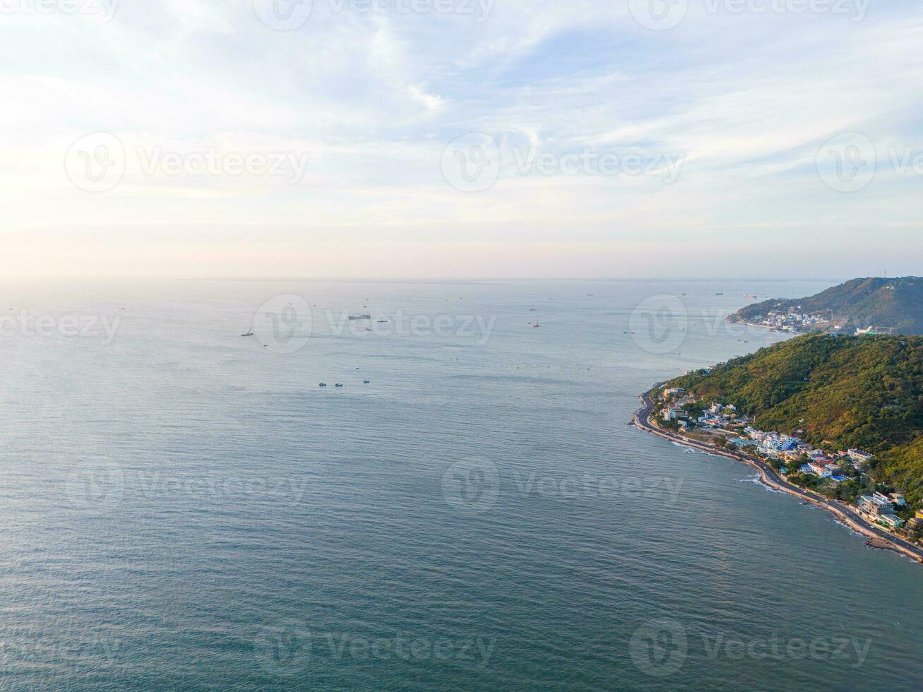 Panoramic coastal Vung Tau view from above, with waves, coastline, streets, coconut trees, Mount Nho in Vietnam behind the statue of Christ the King photo
