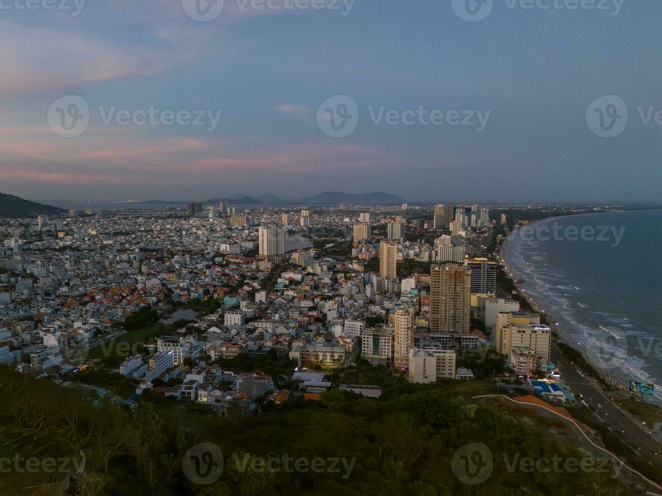 Panoramic coastal Vung Tau view from above, with waves, coastline, streets, coconut trees, Mount Nho in Vietnam behind the statue of Christ the King photo