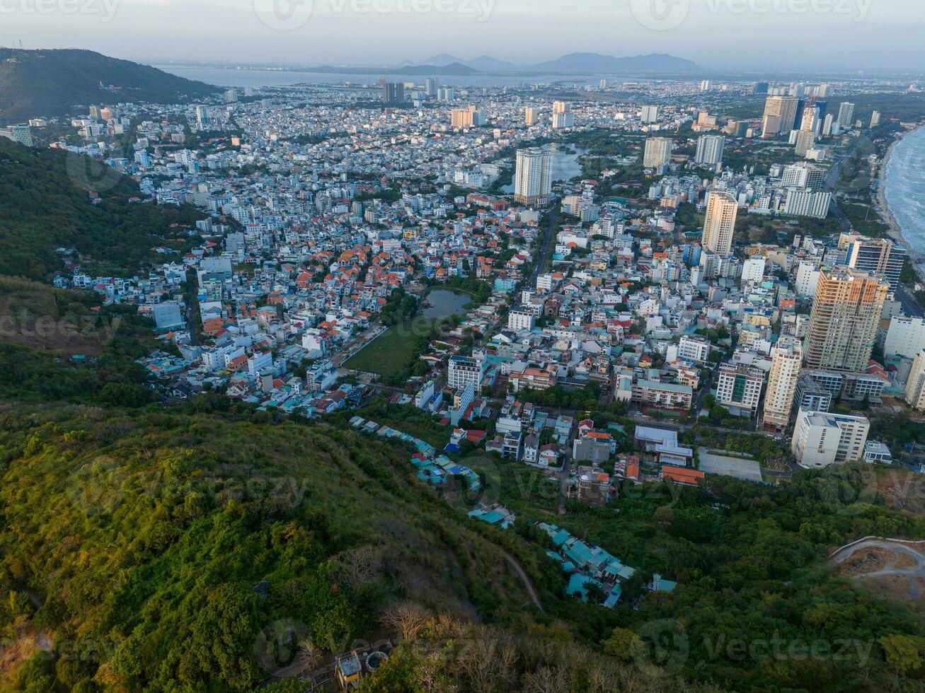 Panoramic coastal Vung Tau view from above, with waves, coastline, streets, coconut trees, Mount Nho in Vietnam behind the statue of Christ the King photo