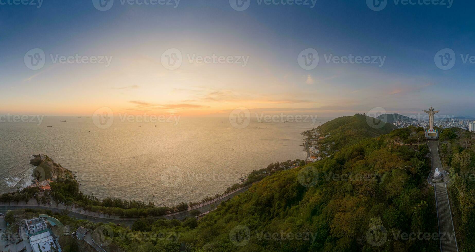 Panoramic coastal Vung Tau view from above, with waves, coastline, streets, coconut trees, Mount Nho in Vietnam behind the statue of Christ the King photo