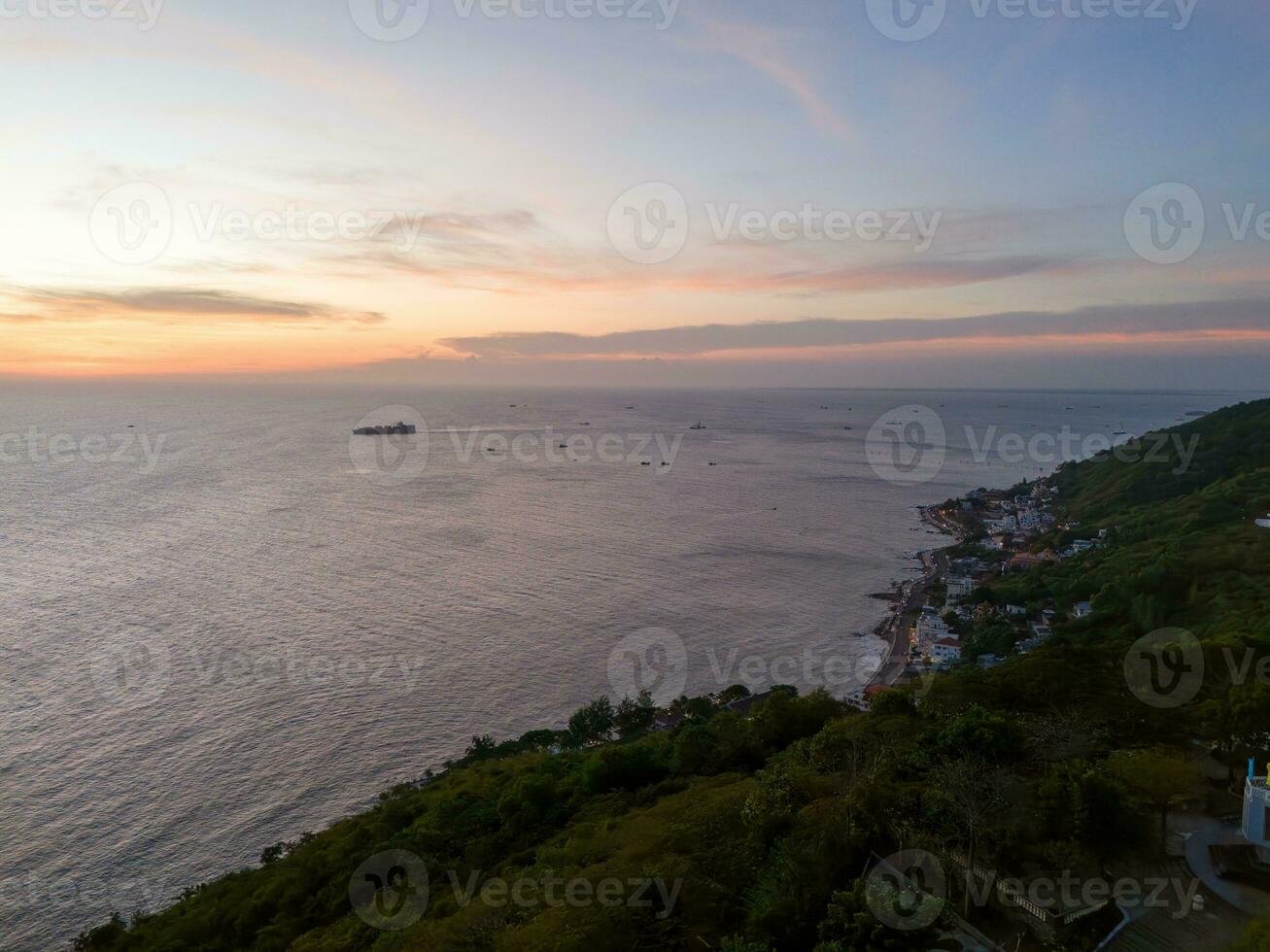 Panoramic coastal Vung Tau view from above, with waves, coastline, streets, coconut trees, Mount Nho in Vietnam behind the statue of Christ the King photo