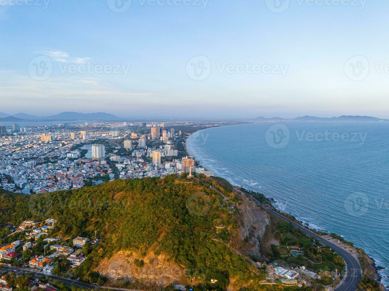 Panoramic coastal Vung Tau view from above, with waves, coastline, streets, coconut trees, Mount Nho in Vietnam behind the statue of Christ the King photo