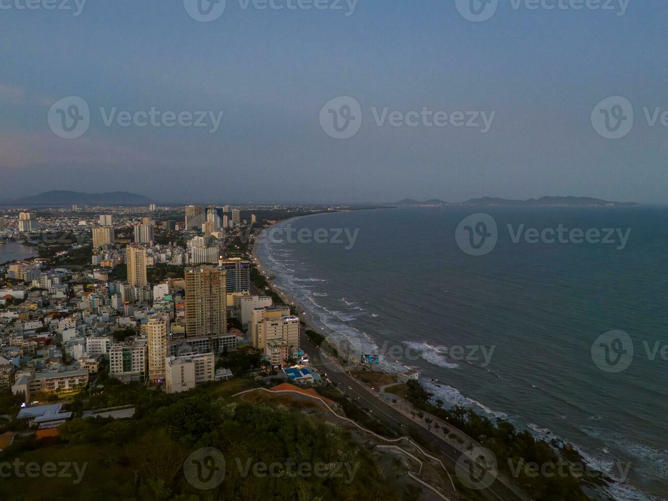 Panoramic coastal Vung Tau view from above, with waves, coastline, streets, coconut trees, Mount Nho in Vietnam behind the statue of Christ the King photo
