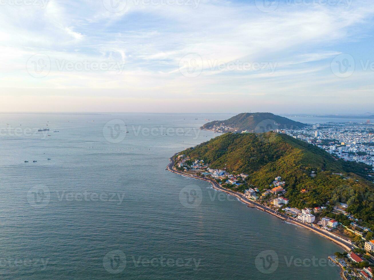 Panoramic coastal Vung Tau view from above, with waves, coastline, streets, coconut trees, Mount Nho in Vietnam behind the statue of Christ the King photo