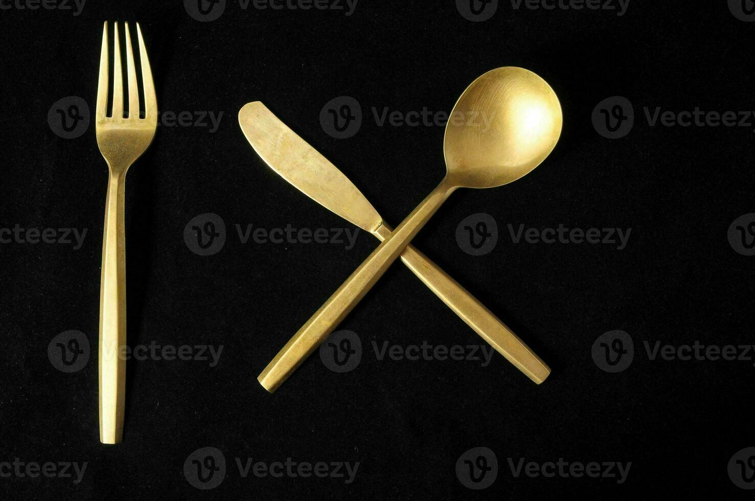 a gold fork and spoon on a black background photo