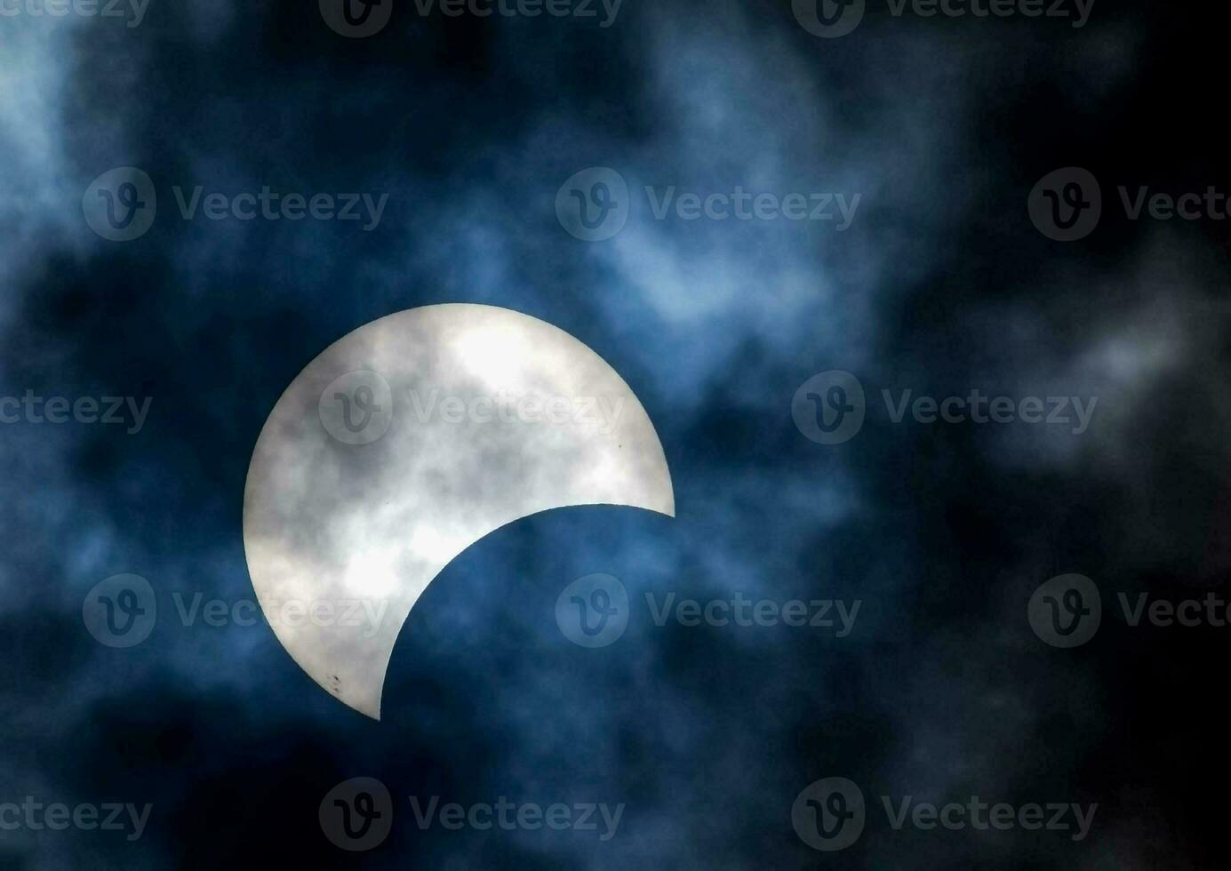 the moon is seen during a partial solar eclipse in the sky photo