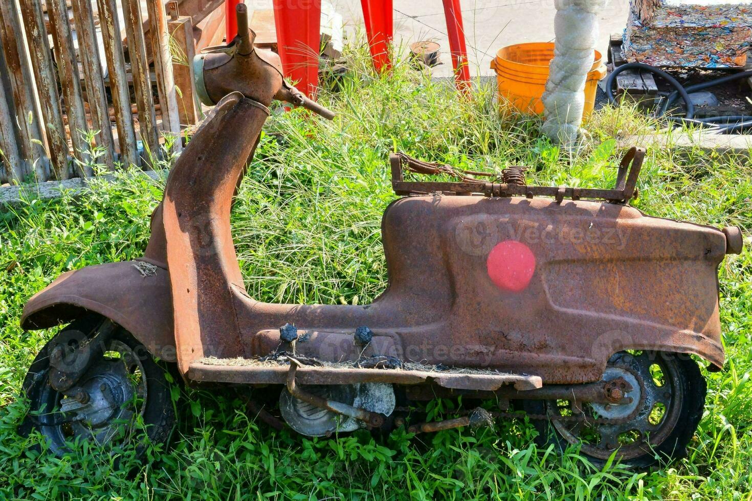 an old rusted scooter is sitting in the grass photo