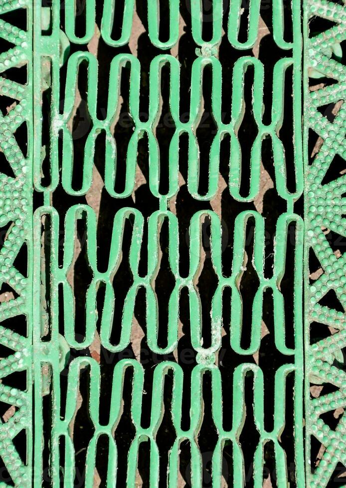 a green metal grate with a pattern of circles photo