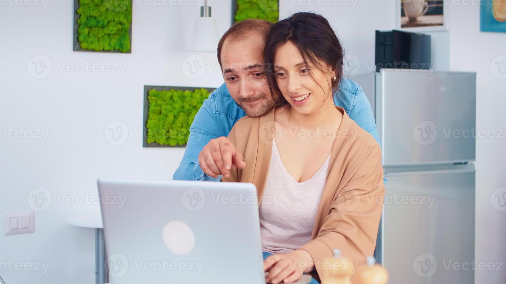Cheerful couple using laptop in kitchen reading online recipe for breakfast. Husband and wife cooking recipe food. Happy healthy together lifestyle. Family searching for online meal. Health fresh salad photo