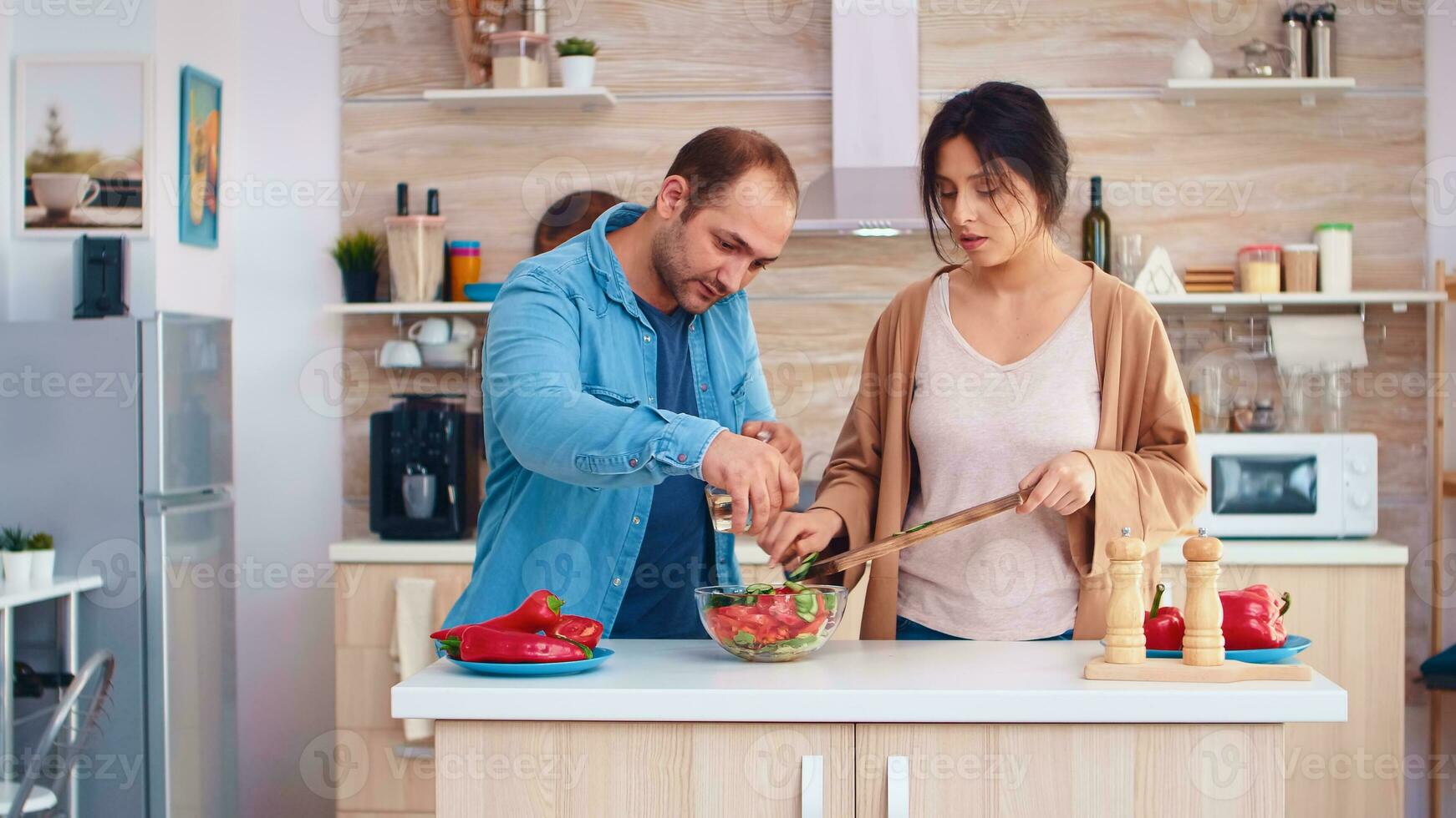 Married couple preparing salad with fresh vegetables in kitchen. Cooking preparing healthy organic food happy together lifestyle. Cheerful meal in family with vegetables photo