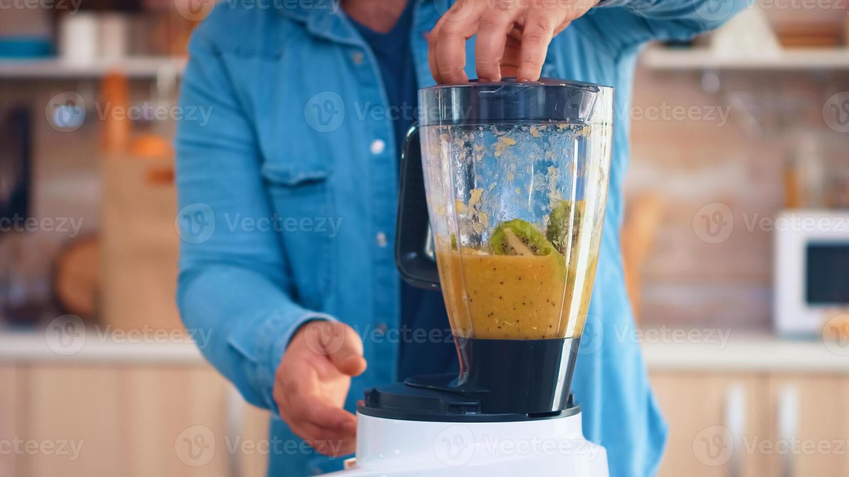 Man mixing fruits with blender for tasty smoothie in kitchen. Cheerful family making together organic healthy fresh nutritious tasty juice for breakfast from fresh fruits while on a diet. photo