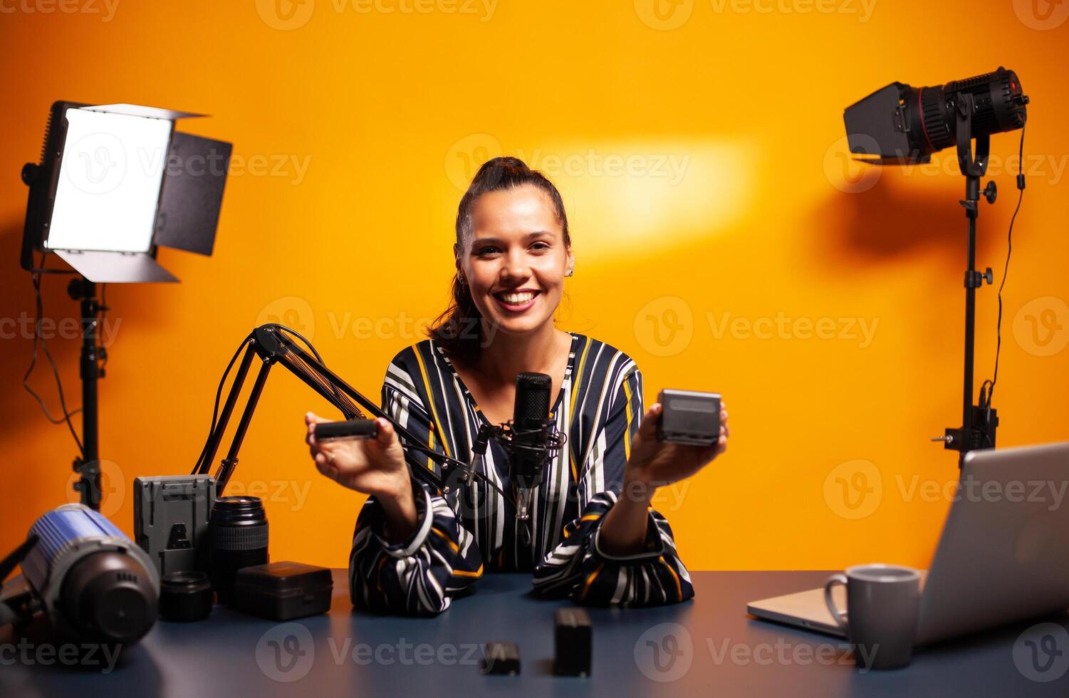 Famous vlogger smiling while recording video about professional accumulators. Presenting review studio portable testing modern batteries li-lion accessory device modern lighting technology. photo