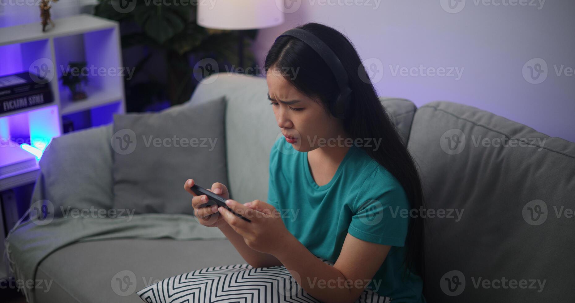 retrato de joven asiático mujer grave jugando un en línea juego frustrado con pérdida o fracaso sentado en sofá en vivo habitación a casa.jugador estilo de vida concepto. foto