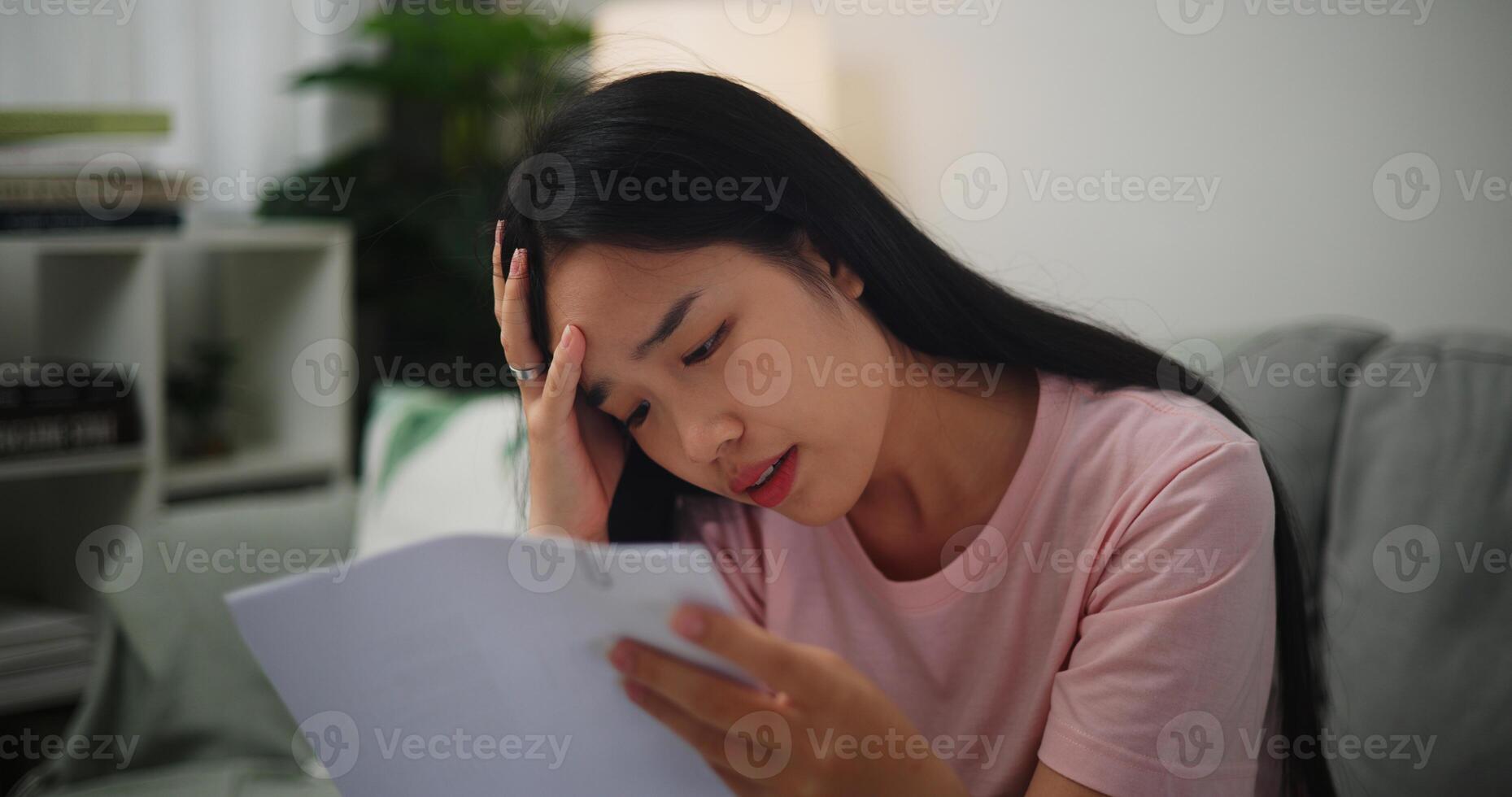 Portrait of Young Asian Woman having financial problems paychecks paper receipt bill statement ,calculating on calculator monthly expenses debt,planning budgets of monthly personal balance at home. photo