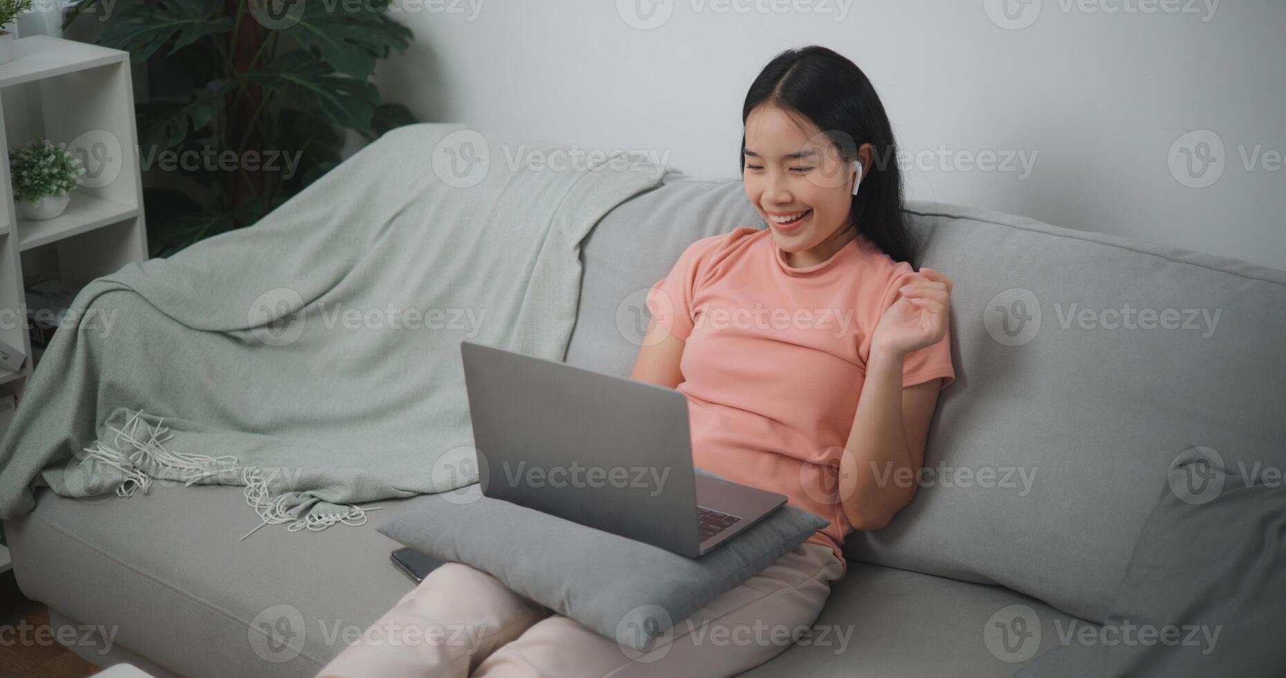 Portrait of Young asian woman making video call via laptop while resting on sofa in living room,Video call meeting with team at home photo
