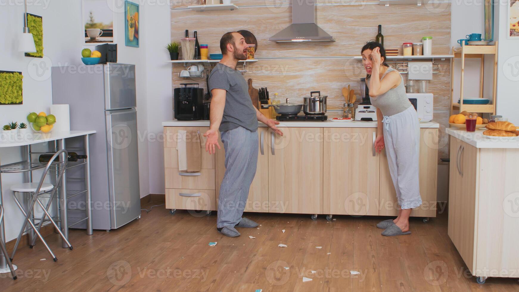Angry wife smashing dish in an argument with husband. Frustrated upset unhappy married woman swearing, smashing dishes, making scandal. Spouse arguing with passion, disagreement conflict and confrontation photo