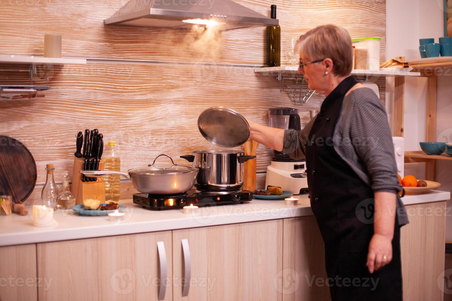 maduro mujer comprobación comida mientras Cocinando eso para cena con mayor marido. retirado mujer Cocinando nutritivo comida para su y hombre a celebrar relación aniversario. foto