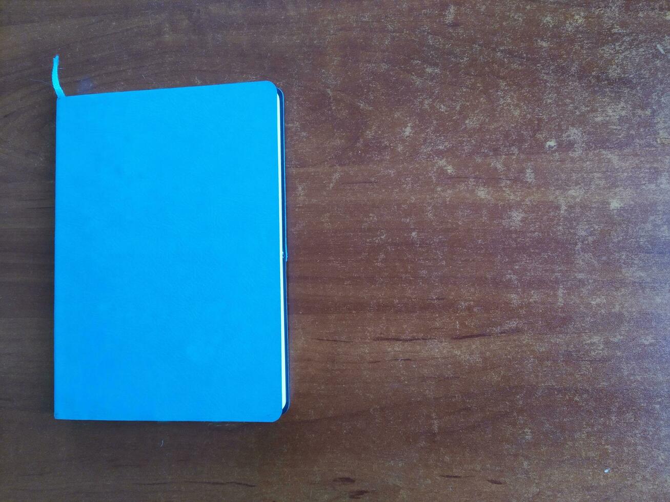 ai generado azul cuaderno en de madera antecedentes. parte superior vista. Copiar espacio para texto foto