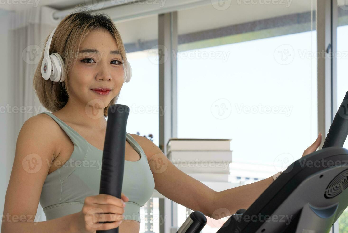 Young Asian Healthy Woman Workout with Elliptical Machine at Home photo