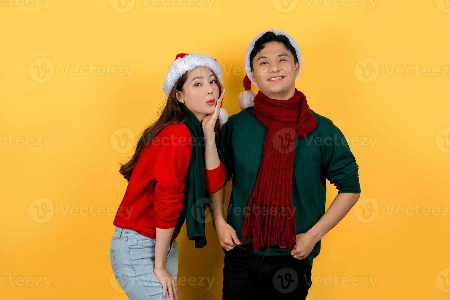 Asian man and woman wearing Santa hats on bright yellow background. Christmas and Happy New Year holiday concept. photo