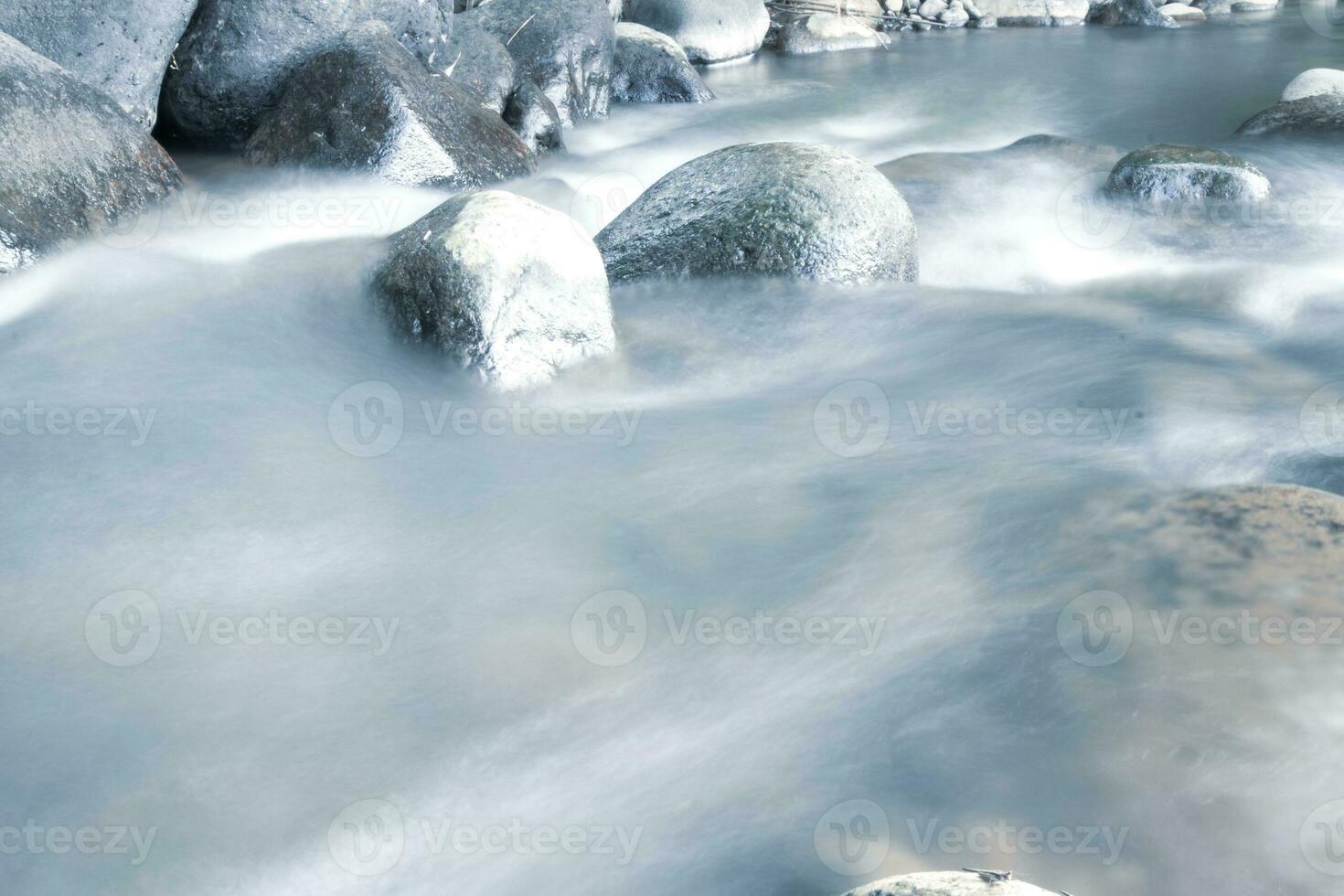 close up of water flowing over cobblestone in river photo