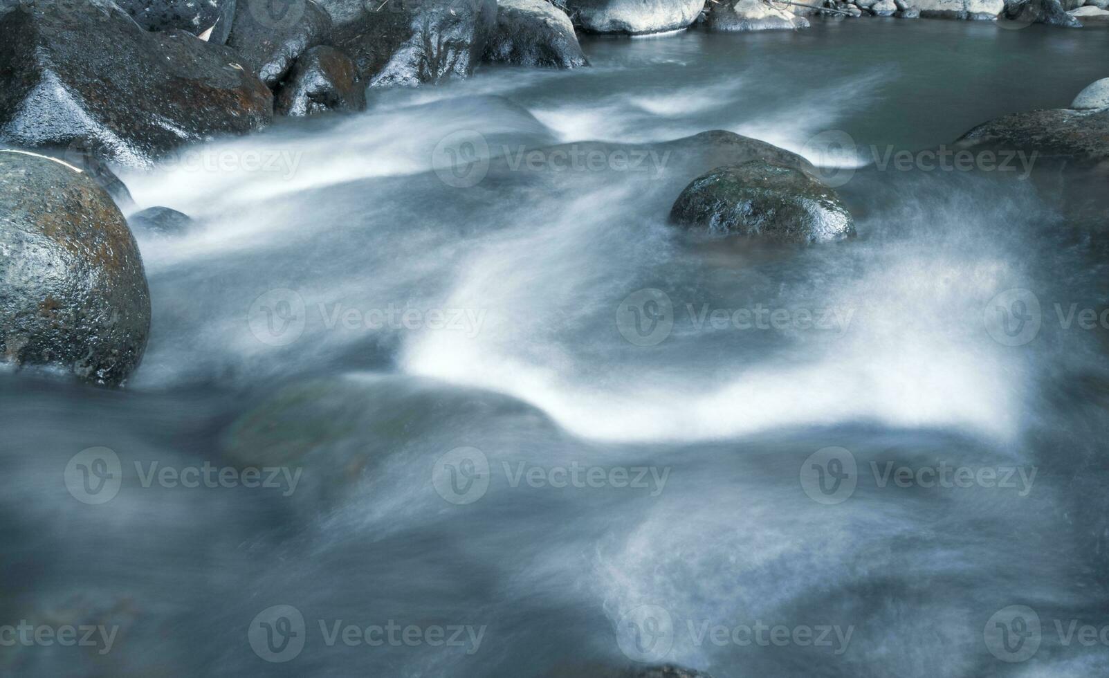 close up of water flowing over cobblestone in river photo