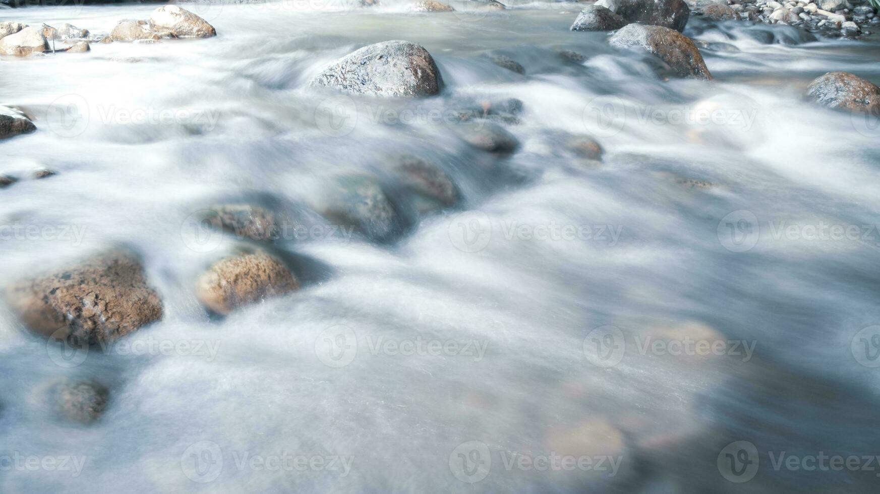 close up of water flowing over cobblestone in river photo