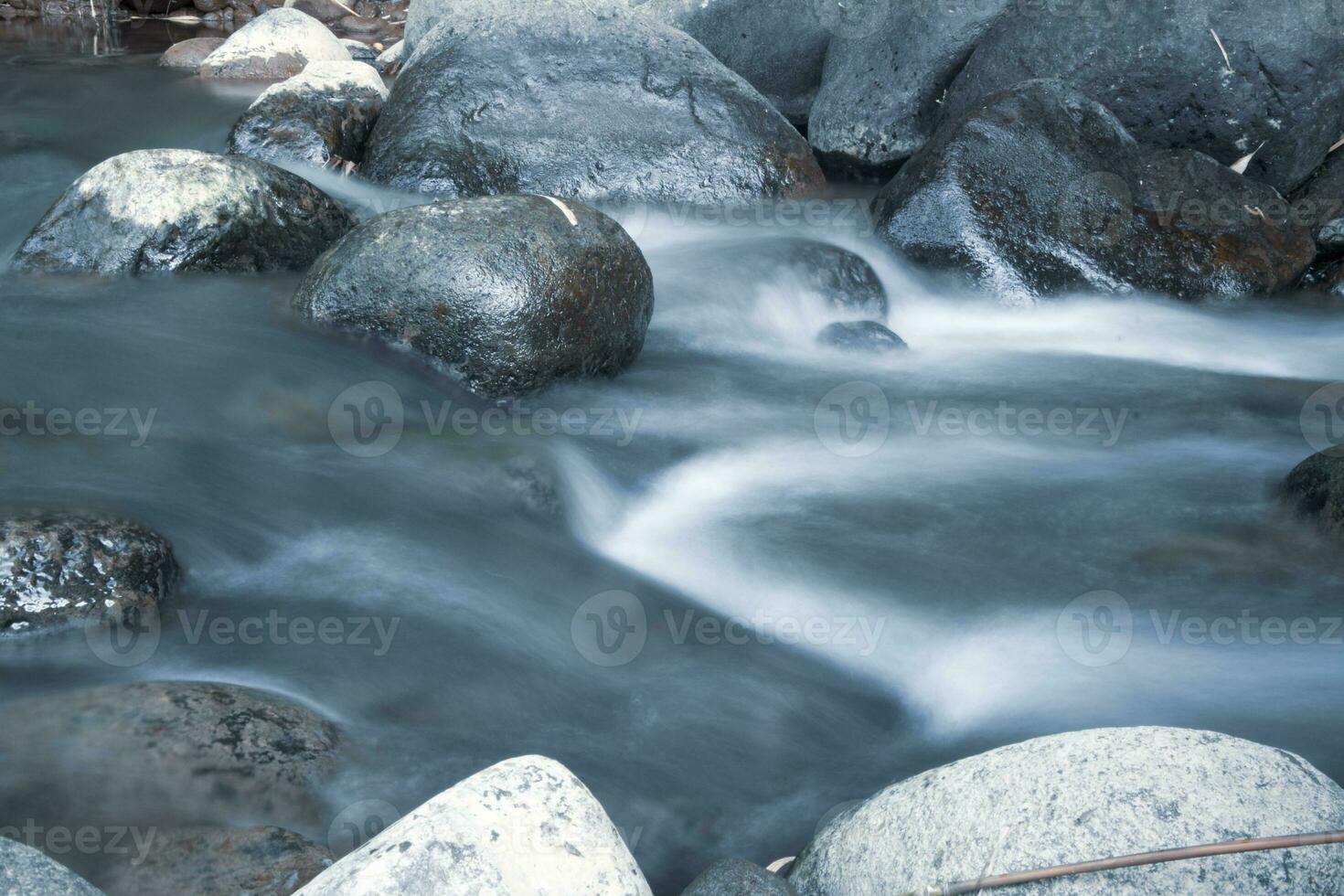 close up of water flowing over cobblestone in river photo