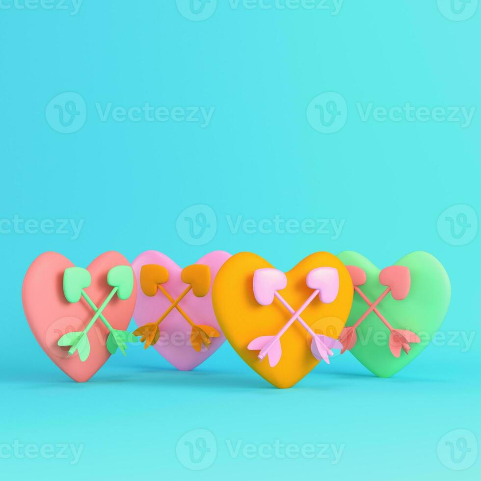 Colorful hearts with crossed cupid arrows on bright blue background in pastel colors photo
