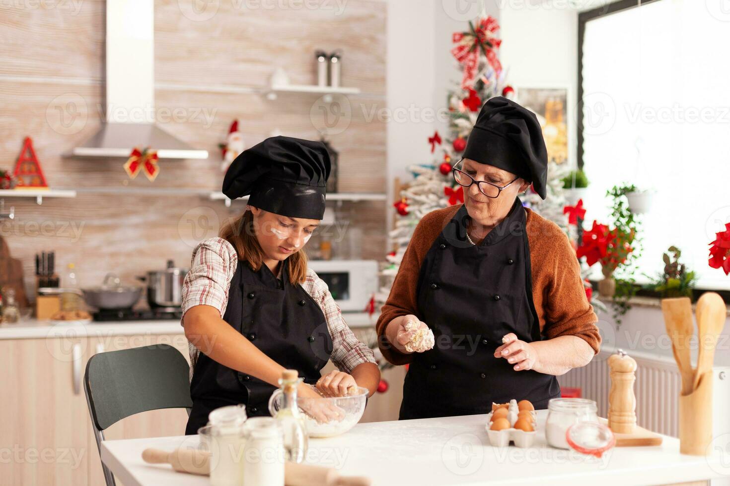 nieto preparando hecho en casa masa con abuela celebrando Navidad temporada juntos en Navidad decorado culinario cocina. niño disfrutando invierno fiesta Cocinando pan de jengibre postre foto