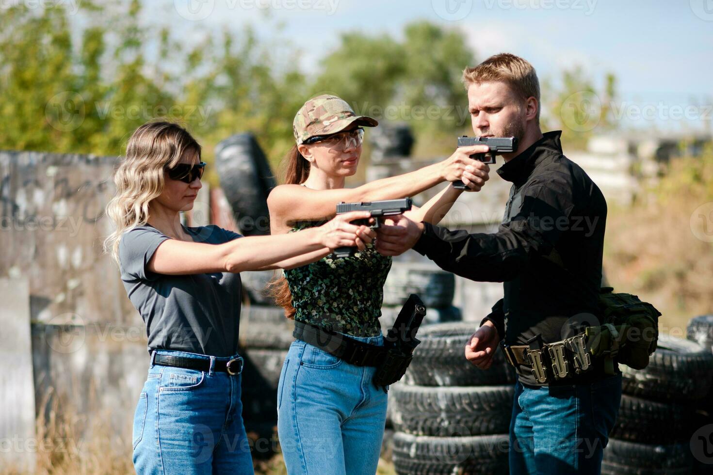 A weapons instructor teaches a girls to shoot a pistol at a firing range photo