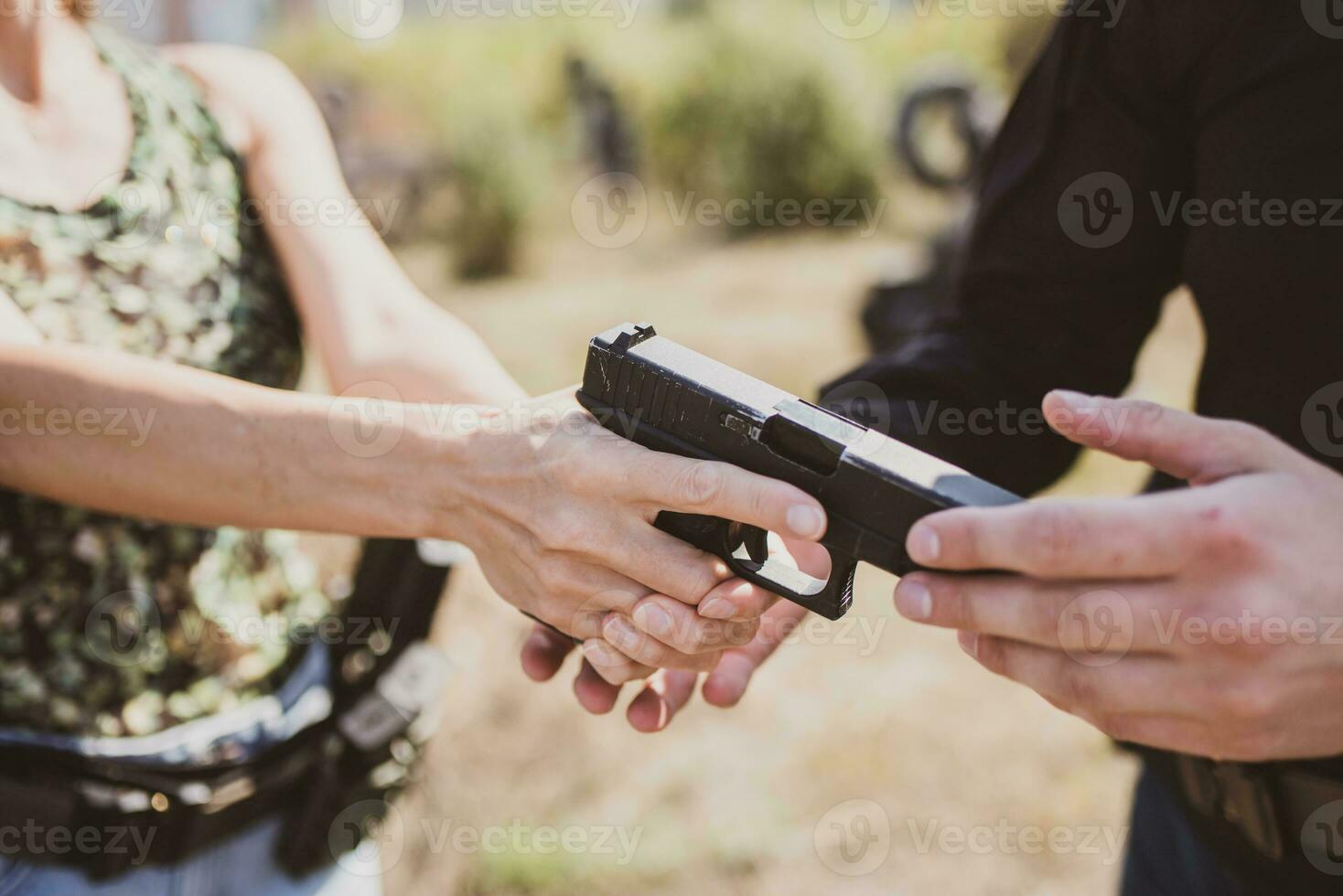 A weapons instructor teaches a girl to shoot a pistol at a firing range photo