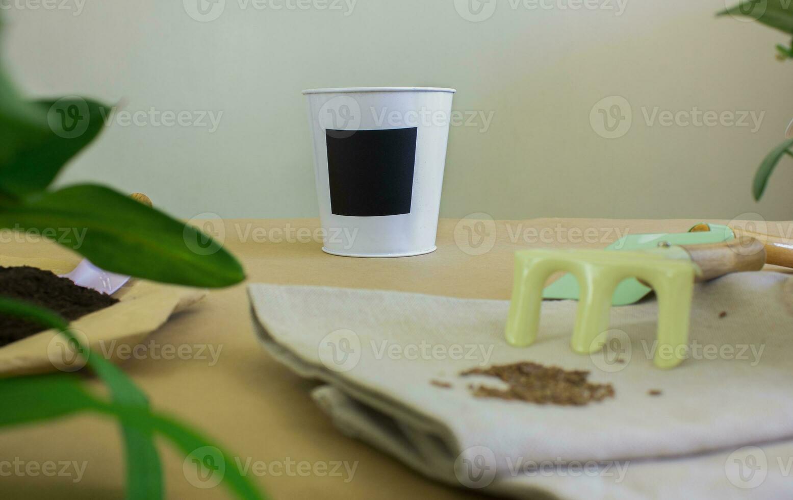Flower pot and gardening tools on light background. photo