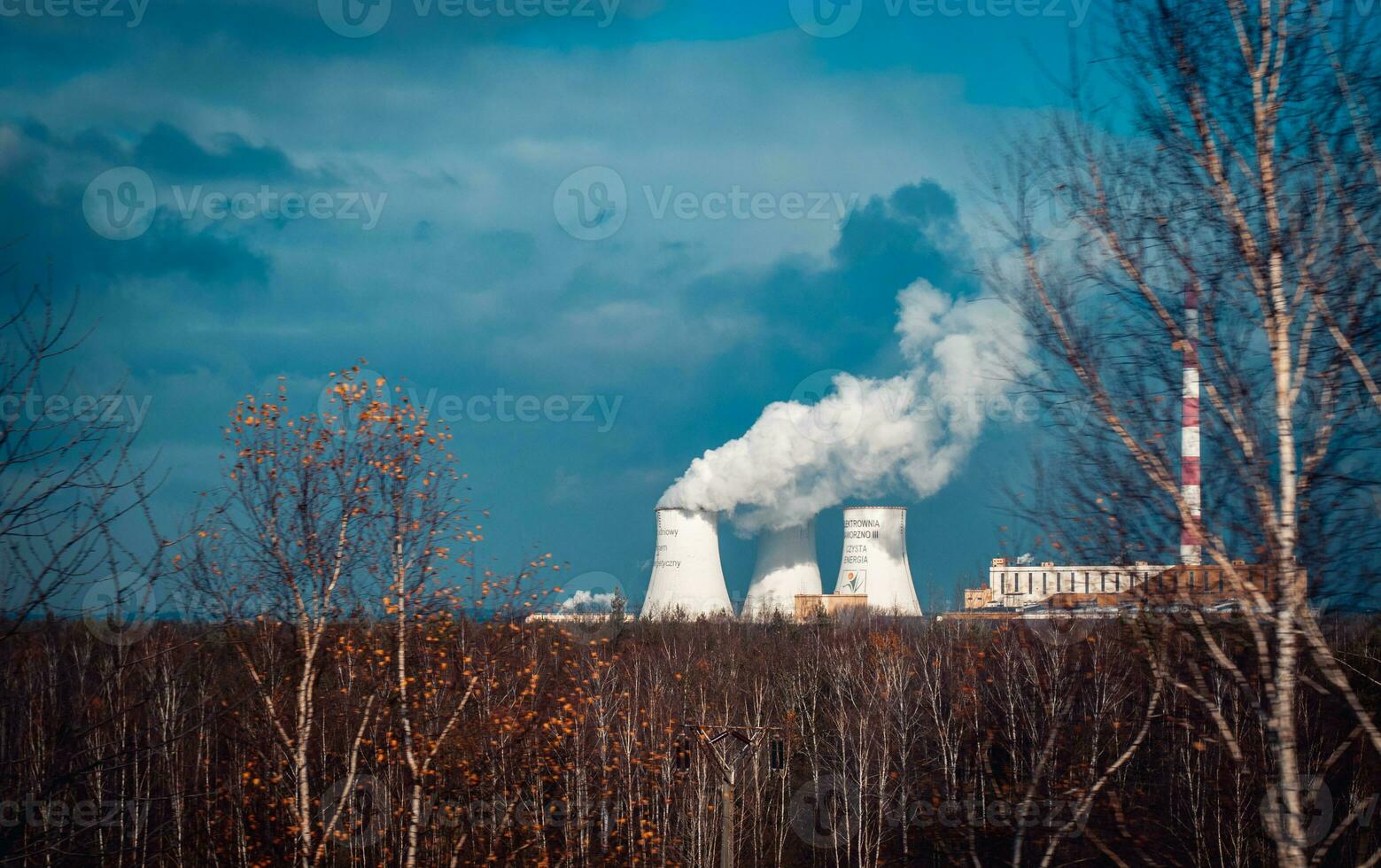Nuclear power plant cooling towers concept photo. Big chimneys. Forest with partly cloudy sky in Polish province. photo