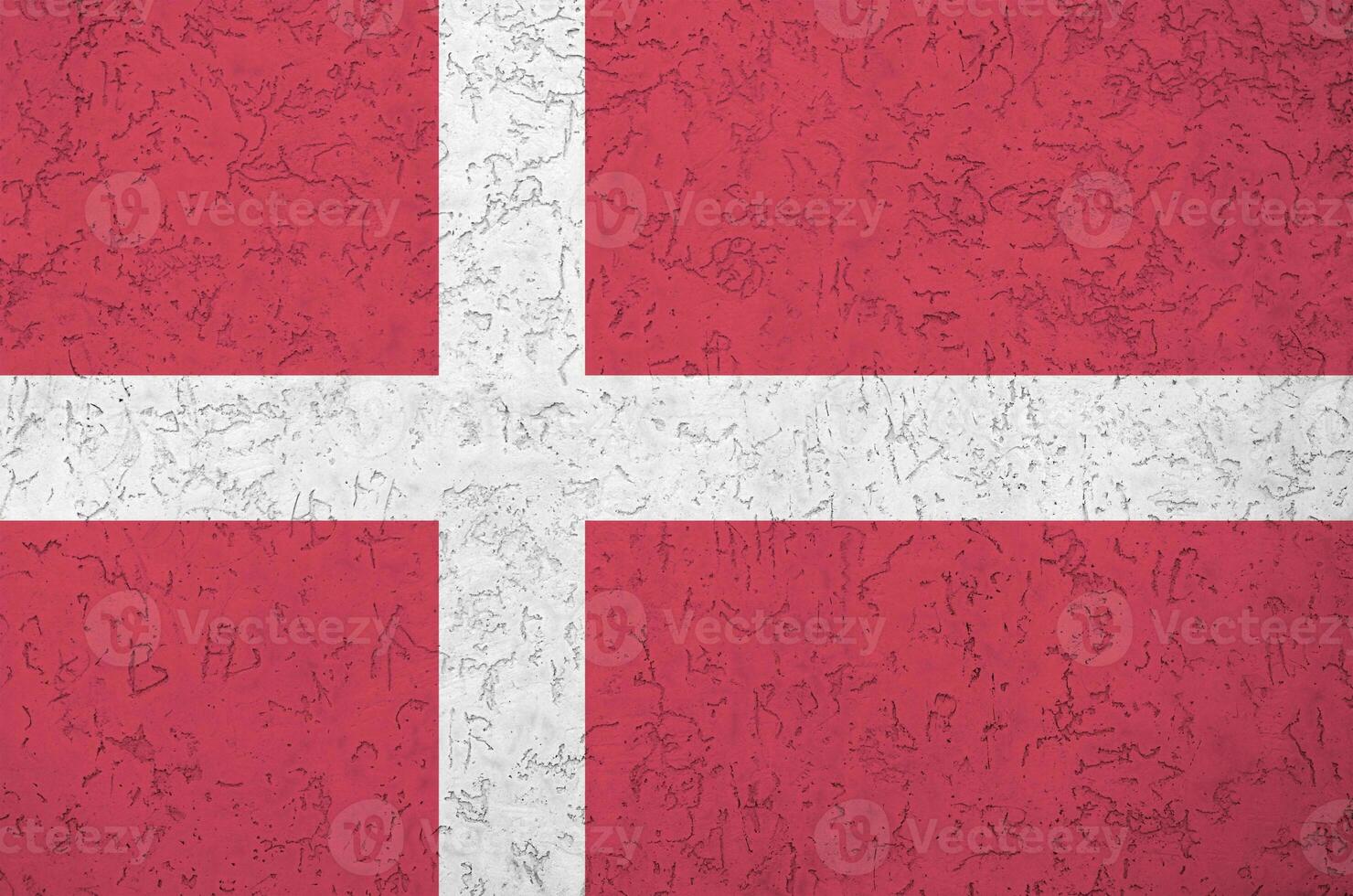 Denmark flag depicted in bright paint colors on old relief plastering wall. Textured banner on rough background photo