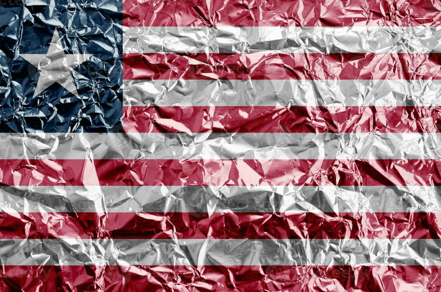 Liberia flag depicted in paint colors on shiny crumpled aluminium foil closeup. Textured banner on rough background photo