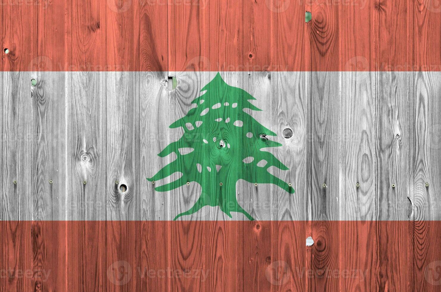 Lebanon flag depicted in bright paint colors on old wooden wall. Textured banner on rough background photo