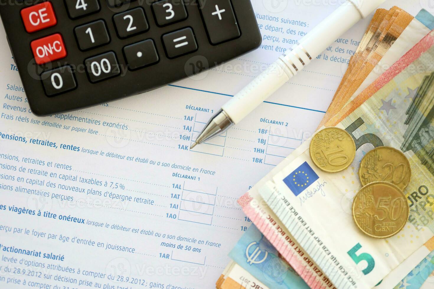 Filling french tax form process with calculator, pen and euro money bills close up. Tax paying period photo