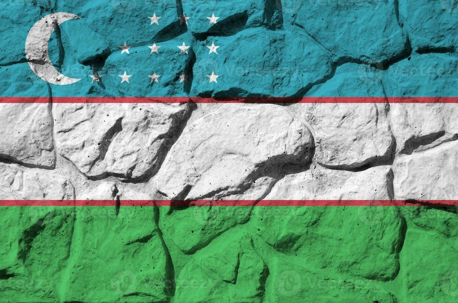 Uzbekistan flag depicted in paint colors on old stone wall closeup. Textured banner on rock wall background photo