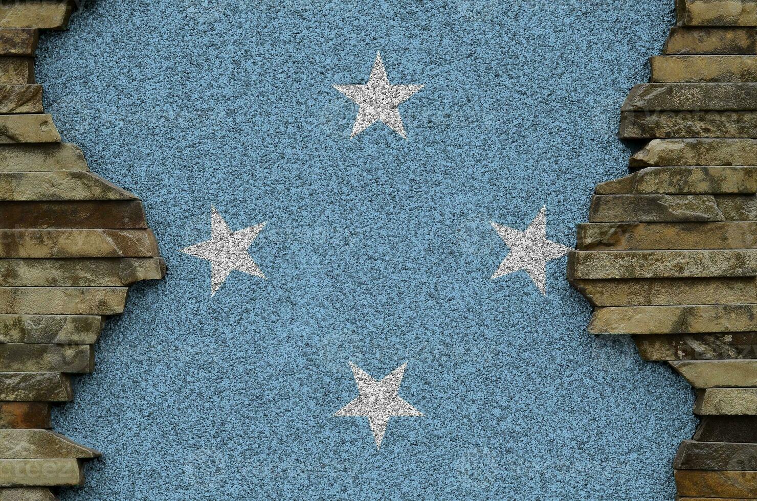 Micronesia flag depicted in paint colors on old stone wall closeup. Textured banner on rock wall background photo