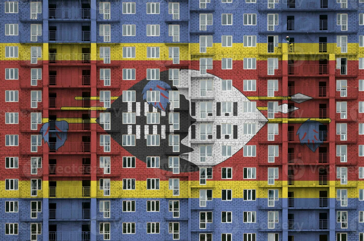 Swaziland flag depicted in paint colors on multi-storey residental building under construction. Textured banner on brick wall background photo