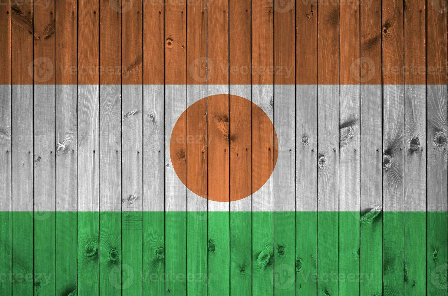 Niger flag depicted in bright paint colors on old wooden wall. Textured banner on rough background photo