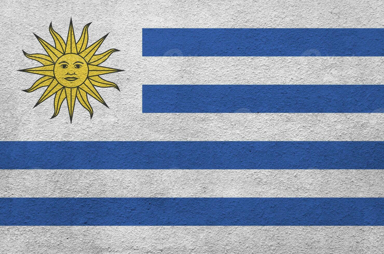 Uruguay flag depicted in bright paint colors on old relief plastering wall. Textured banner on rough background photo