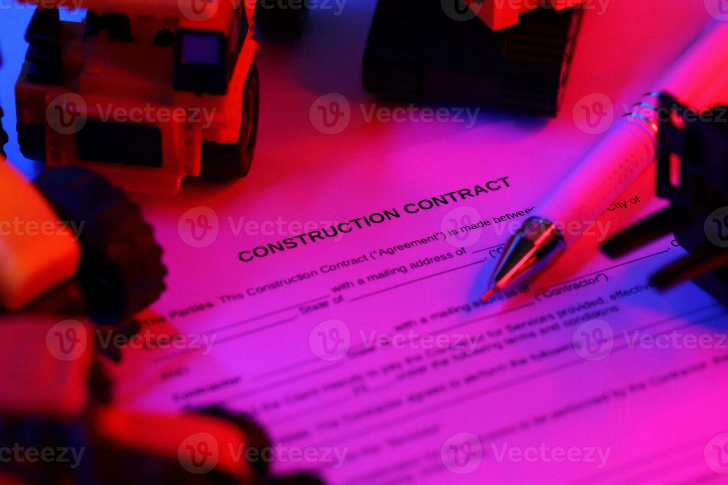 Construction contract with pen lies on table with many yellow construction and service toy vehicles photo