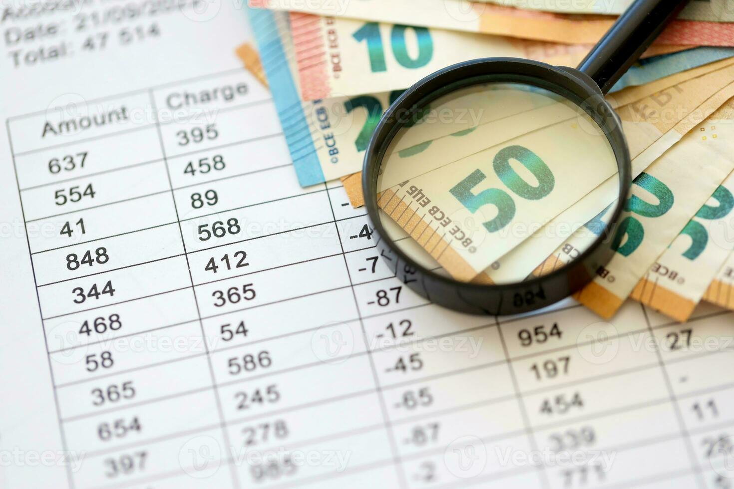 Business and savings concept with many euro money bills and magnifying glass photo