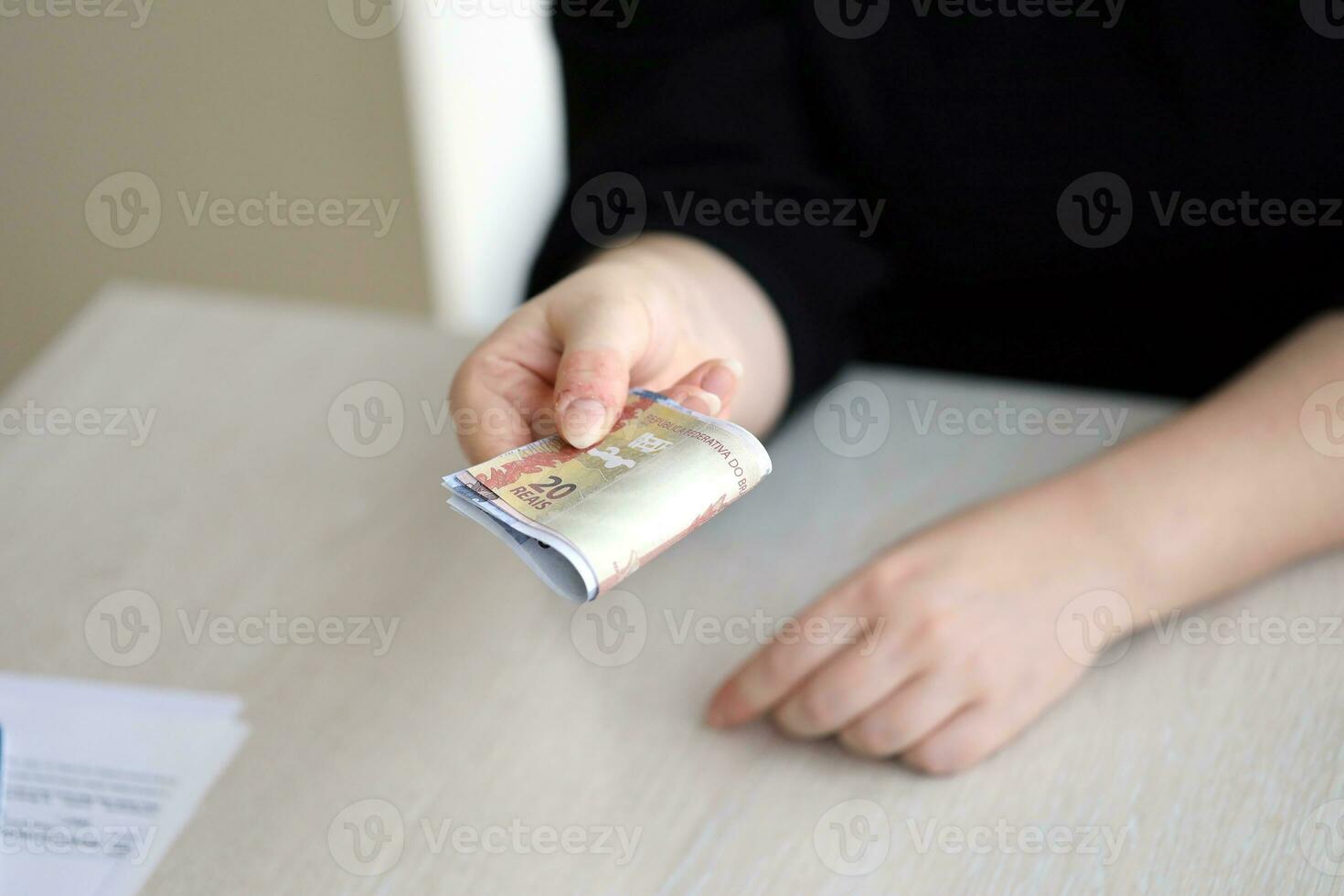 Brazilian money bills in woman hand. Female gives bunch of brazilian reais to us photo