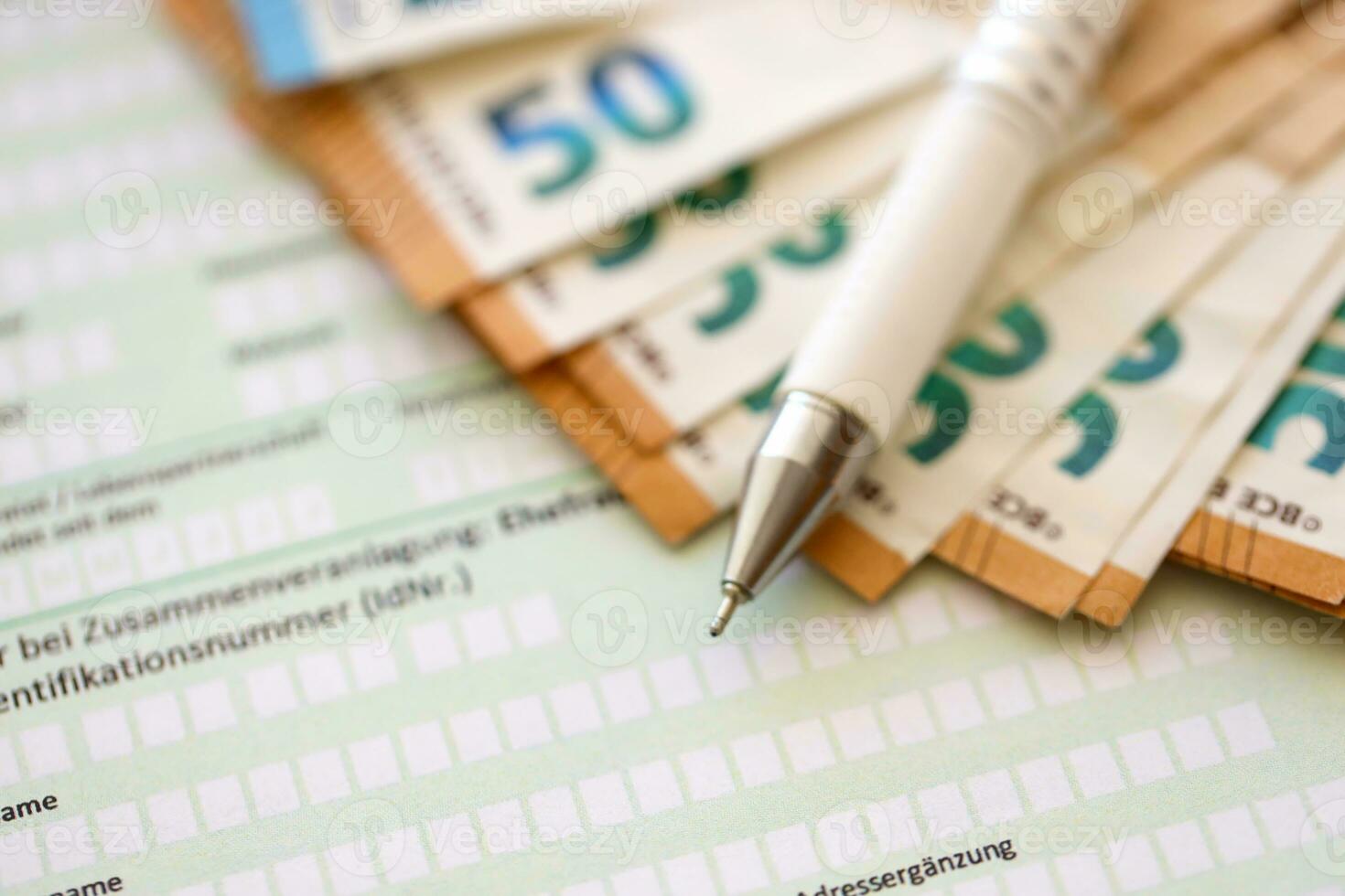 Filling german tax form process with pen and euro money bills close up. Tax paying period photo