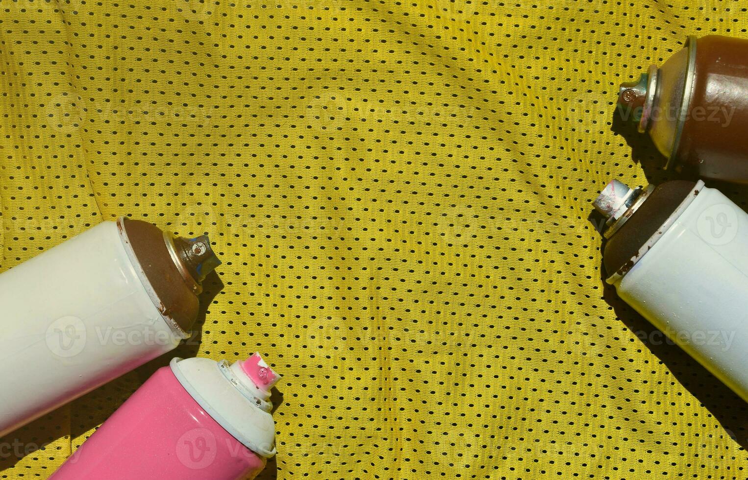 Several used aerosol paint sprayers lie on the sports shirt of a basketball player made of polyester fabric. The concept of youth street art, active sports and eventful lifestyle photo