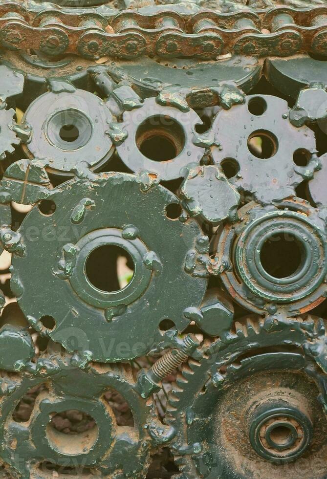 A composition of a set of gears and car parts that are welded to each other and painted green. Grunge steampunk texture photo