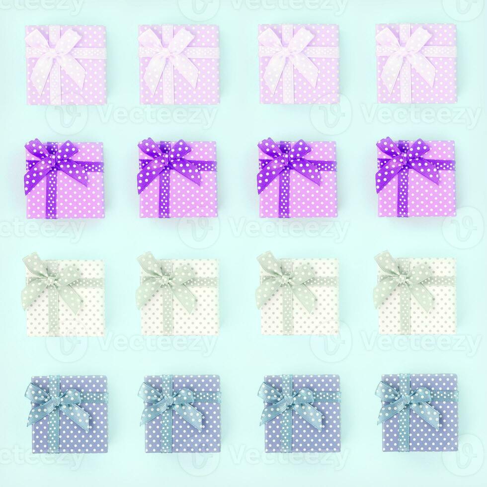 Piles of a small colored gift boxes with ribbons lies on a violet background. Minimalism flat lay top view pattern photo